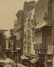 Narrow street in Cairo, showing meshrebeeyehs (lattices over windows). 1880