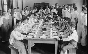 Naval Cadets sit at long table with bowls in front