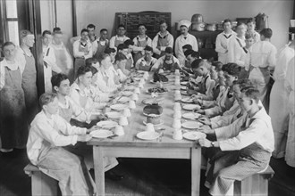 Naval Cadets sit at long table with bowls in front