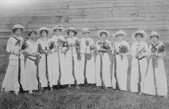 Nemours Women's Trap shooting Club in elegant dress hold both nosegays and rifles.