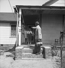 Newport News, Virginia. Black shipyard worker leaving his rural home for the shipyards with his lunch box 1942