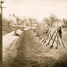 Petersburg, Va. Row of stacked Federal rifles; houses beyond 1865