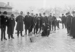 Curling in Central Park with Men having Brooms at the ready over the ice.