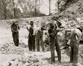 Prisoners breaking up rocks at a prison camp or road construction site 1940