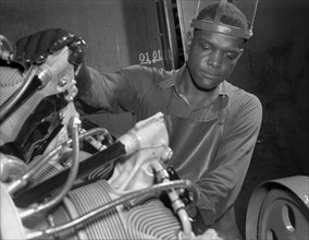 Production. Aircraft engines. A young Black worker stands ready to wash or "degrease" this airplane motor prior to its shipment. He's an employee of a large Midwest airplane plant. Melrose Park, Buick...