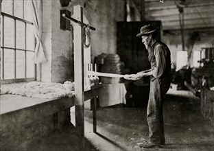 Rhodes Mfg. Company, Lincolnton, N.C. Old man inspecting yarn. 1908
