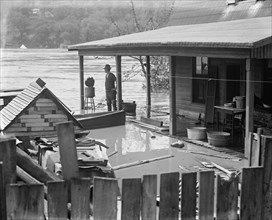 Rising River Floodwaters approach a man who stands on his front porch 1924