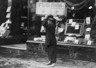 Scavenger hold a box of scavenged wood aloft. 1916