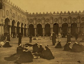 Several groups of theologians, many seated, some writing, in the courtyard of the al-Azhar Mosque. 1880