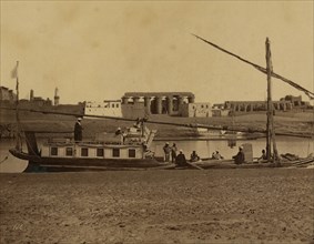 Several men on boat docked at water's edge, temple ruins of ancient Thebes in background, Luxor, Egypt. 1880