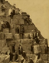 Several people gathered at the base of the Great Pyramid, others climbing 1880