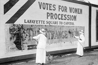 Suffragettes uses Long Brushes to Post a Billboard announcing a "Votes" For Women" Parade 1914