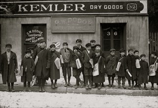 Sunday noon. Some of the newsboys returning Sunday papers. In front of Dry Goods Store and Carpenter Shop 1909