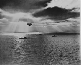 Sunset over the Atlantic finds another United Nations convoy moving peacefully towards it destination. A U.S. Navy blimp, hovering watchfully overhead, is on the lookout for any sign of enemy submarin...