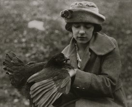 Susie Kellison, raising chickens. Examining the wing and looking for smut. 250 of these boys and girls in the Club work in this Co. 1921