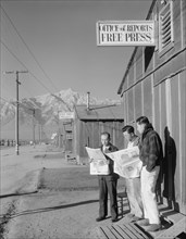 Roy Takeno (Editor) and group reading Manzanar paper [i.e. Los Angeles Times] in front of office, Yuichi Hirata, Nabuo Samamura 1943