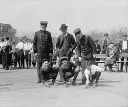 Three Young Boys Crouch in front of three men - the boys hold their marbles 1923
