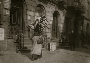 Tired woman with heavy load of home-work. Lafayette St., near Astor Place.  1912