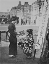Toddler in front of Shop sign sells flowers to a kimono wearing young lady