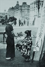 Toddler in front of Shop sign sells flowers to a kimono wearing young lady