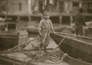 Truant hanging around boats in the harbor during school hours. 1909
