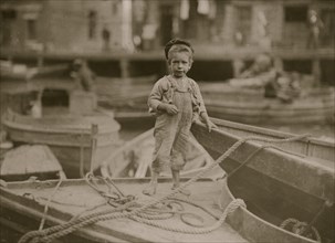 Truant hanging around boats in the harbor during school hours. 1909
