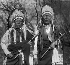 Two Cheyenne Chiefs in War Bonnets hold peace pipes 1924