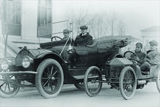 Two men in a large auto are side by two men in a Miniature Auto 1922