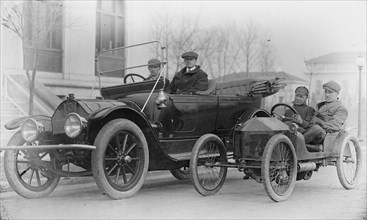 Two men in automobiles; i.e. two in a large car and two in a miniature vehicle 1920