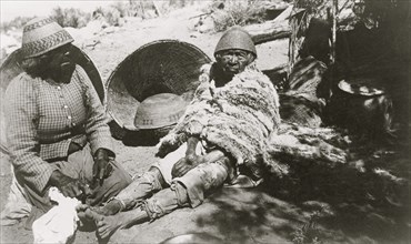 Two old Paiute Indian women with baskets and woven hats, one identified as Teha 1902