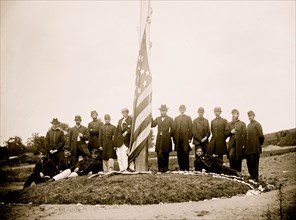 Washington, D.C. Signal Corps officers lowering flag at their camp near Georgetown; Gen Albert J. Myer, in civilian dress, at right of pole 1865