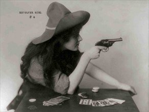 Young Cowgirl Hold Pistol Over a table of Playing Cards 1912