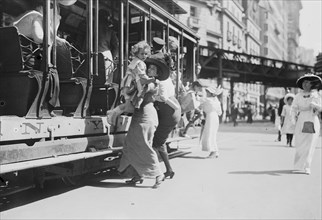 Woman lifts child off of an open sided Trolley Car on New York's Broadway