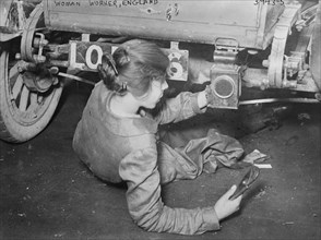 Woman mechanic in England during the great war; show works under a vehicle 1917