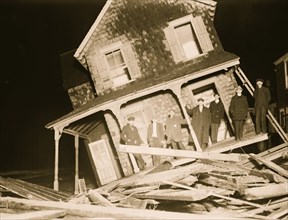 Wrecked Cottage at Seabright with men on tilted front Porch