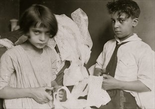 Young boy and young girl cutting fabric in work taken in at home in their tenement 1924