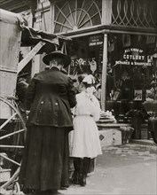 Young vendor sells goods outside of a cutlery store 1910