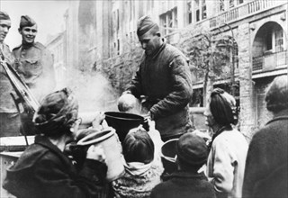 A red army soldier distributes hot food to berlin residents, april, 1945, germany, world war 2.