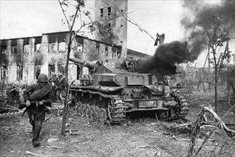 Red army men dash past a disabled and burning nazi tank, stalingrad world war ll.