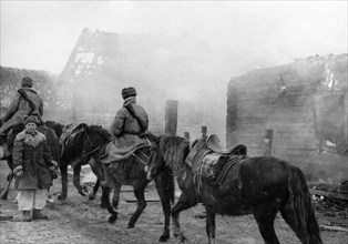 Advancing soviet troops going by peasant cottages set fire by retreating germans, world war ll.