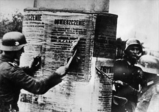 Nazi invasion of poland, september 1939, german soldiers tearing down a polish proclamation, world war 2.