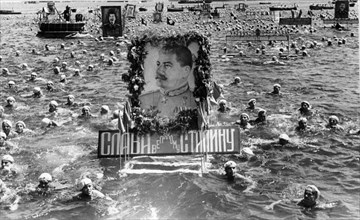 Soviet sailors swimming with floats with portraits of stalin in celebration of ussr navy day, sevastopol, ussr, july, 1950.