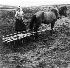 A peasant woman with horse tilling the soil on a farm in voronovo village on the volga in pre-revolutionary russia, 1900.