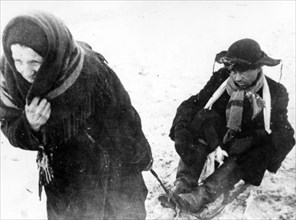 world war ll: woman pulling someone (her son?) weakened by hunger on a sled during the siege of leningrad.