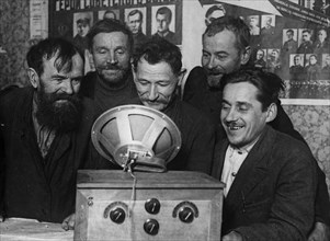 Peasant farmers listen to the first radio at a collective farm in the russian federation, 1930.