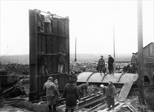 Post-war donbass heals it's wounds, setting up a cylindrical head-frame, designed by engineer zherbin, at the dzerzhinsky colliery no, 12 in donbass, ussr, 1940s.