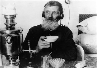 A worker of the 'sibir' match factory with a radio set, drinking tea from his samovar, near tomsk, sibeia, 1928.
