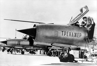 September 1966: a north vietnamese student pilot in a non-flying mig-21 fighter jet trainer, with him is his soviet flight instructor, lettering on fusilage: 'trainer'.
