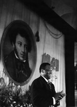 American singer paul robeson speaking in front of a portrait of pushkin at the hall of columns of the house of trade unions in moscow during the celebrations of the 150th anniversary of the poet's bir...