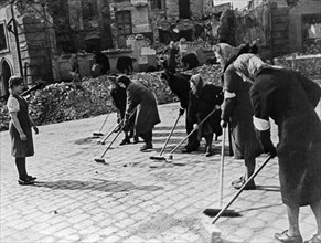 German women sweeping a berlin (?) street after the german surrender at the end of world war 2 in 1945, they are being supervised by marusia kuznetsova, a russian girl who spend more than 2 years as a...